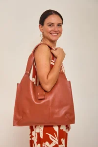 Mulher segurando bolsa de couro marrom.