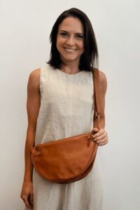 Mulher sorrindo com bolsa de couro marrom