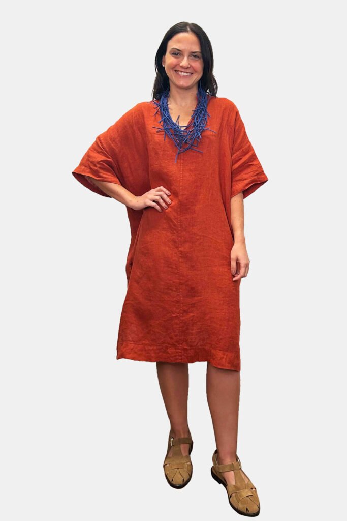 Mulher usando vestido laranja e colar azul